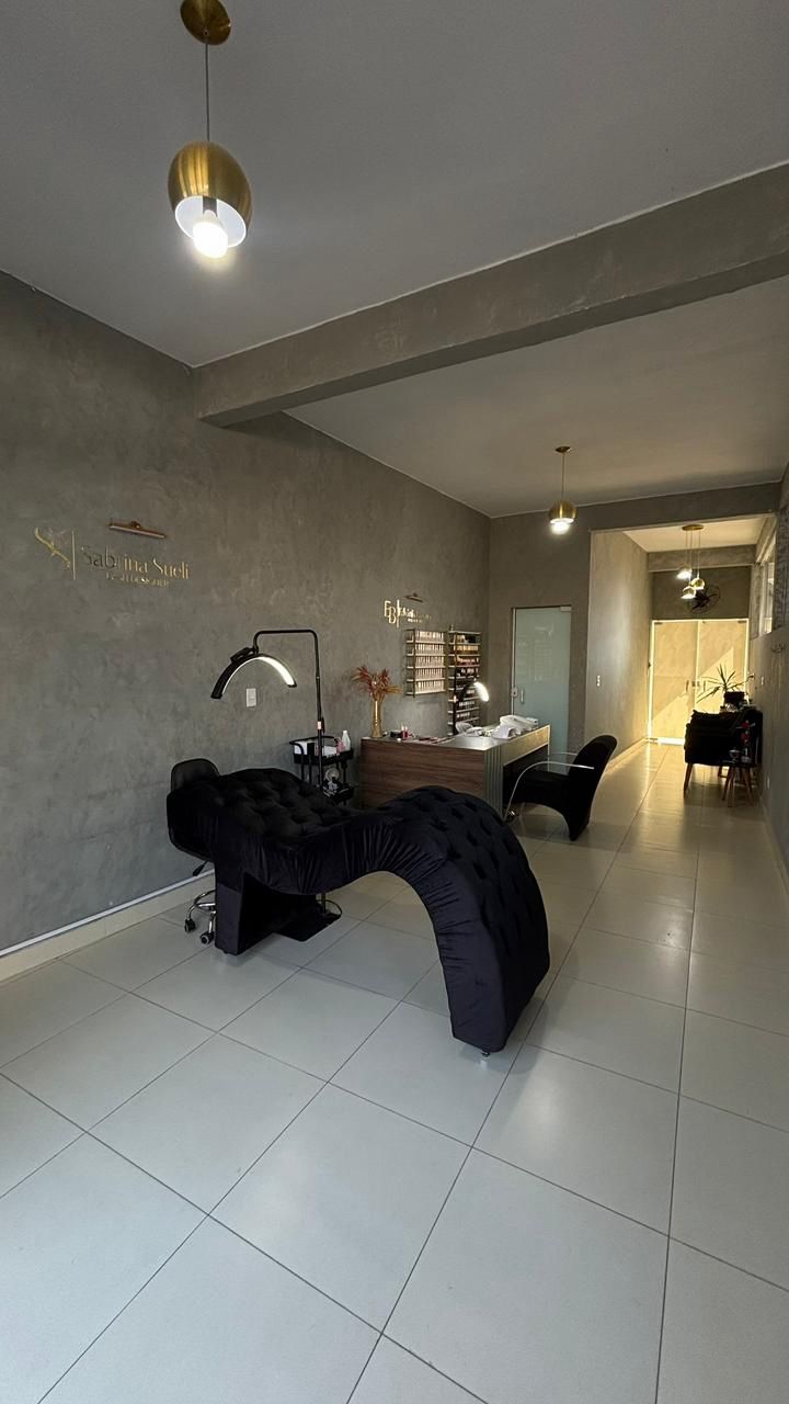 Sala de atendimento do studio com maca preta, ring light e marca Sabrina Sueli na parede