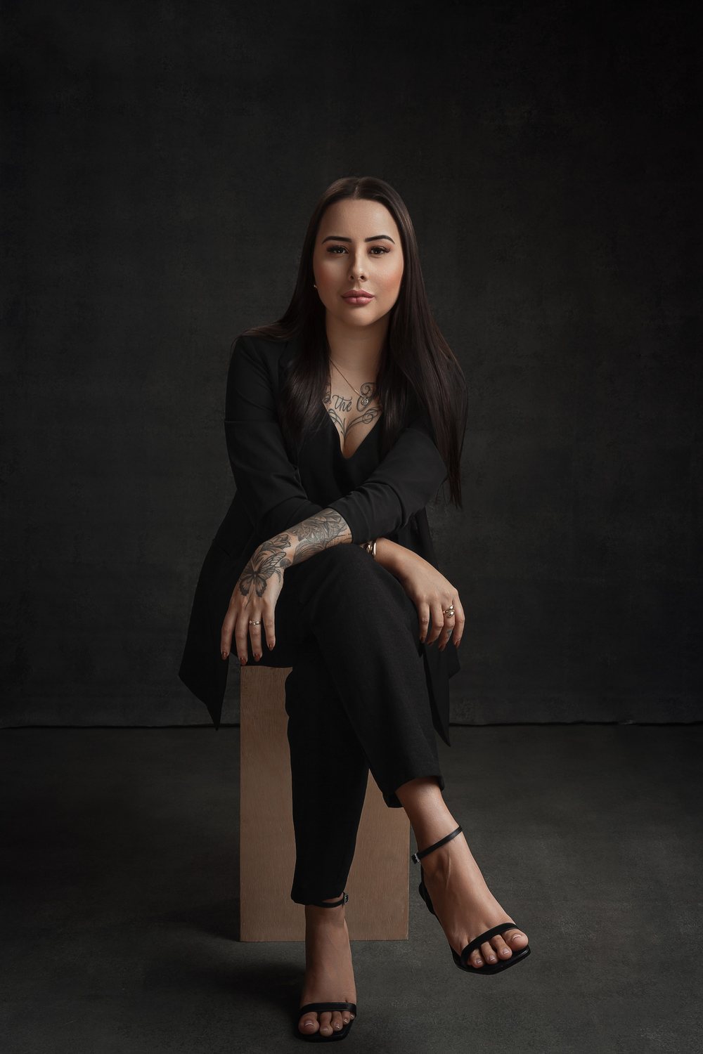 Sabrina Sueli sentada, em retrato de estúdio com fundo escuro